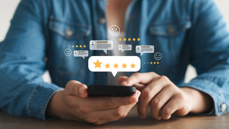 Marketing team monitoring and responding to customer reviews on mobile devices, managing five-star ratings and feedback through a review management platform to strengthen brand reputation and online presence.