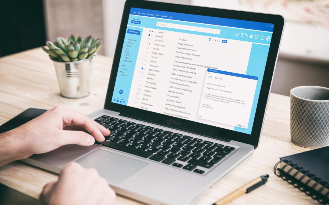Man working on a laptop looking at a client mail list in an office setting.